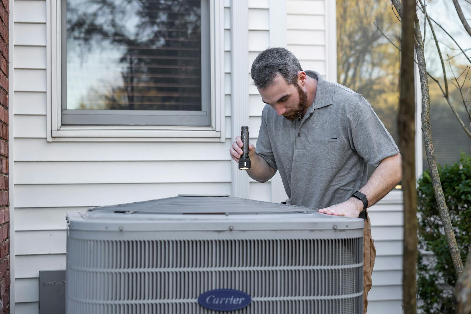 HVAC technician inspecting outdoor AC unit for spring maintenance in Ottawa